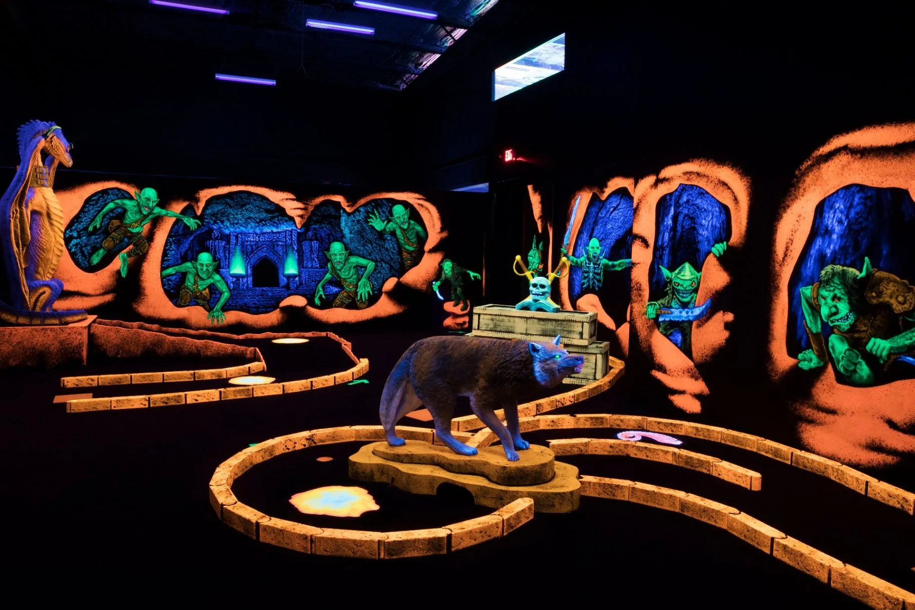 Glowing wolf sculpture and fantasy mural on the mini golf course