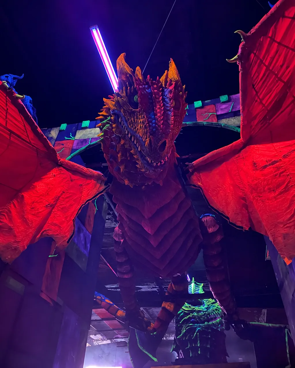 A neon-lit dragon sculpture inside Cooper's Kingdom's blacklight mini golf course